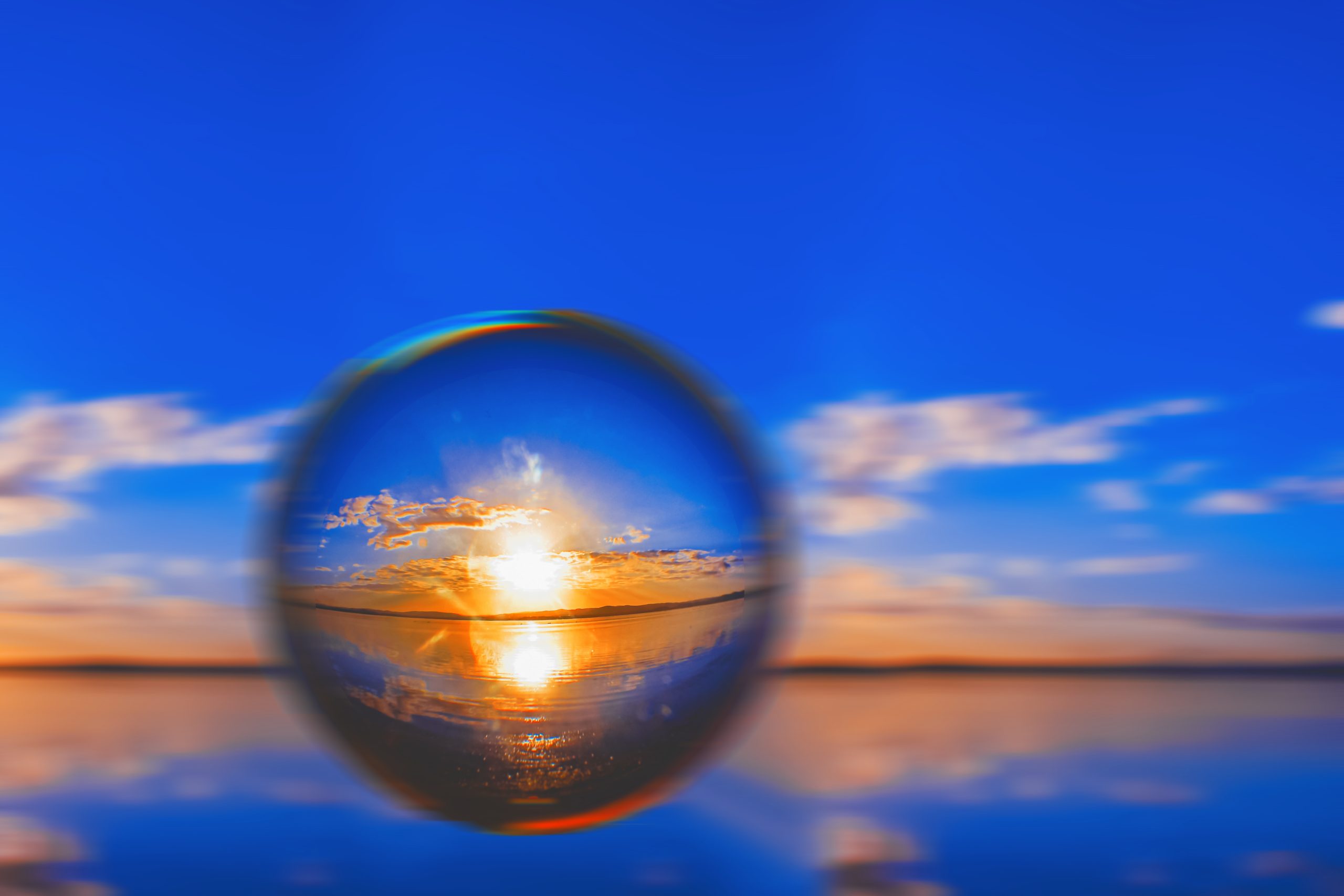 A creative lens ball photography of the sunlight on the horizon with clouds around in the blue sky