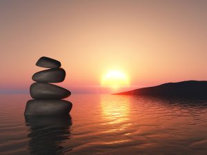 3D render of a landscape with balancing pebbles in sunset sea